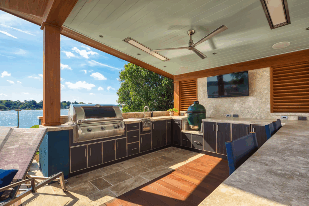 Luxury Florida outdoor kitchen and patio with weather-resistant cabinetry, built-in grill, and waterfront view.